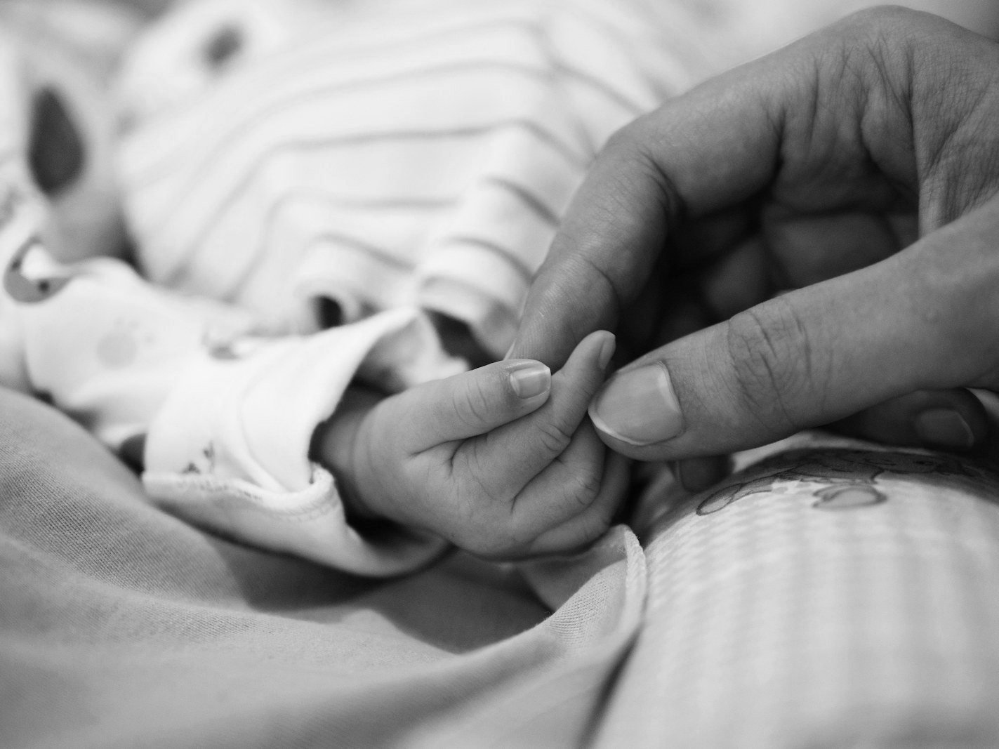 Surrogacy law Bangladesh — newborn baby's hand and identity documents for birth registration