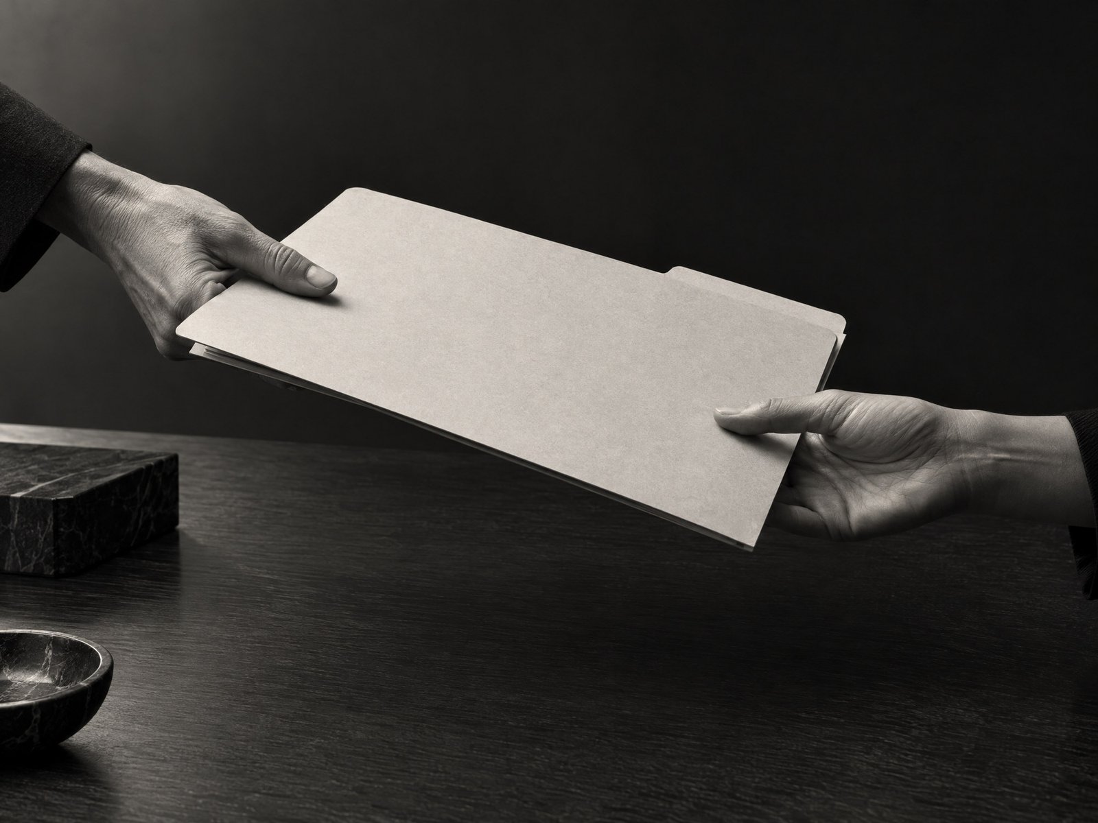 Two unidentifiable hands transferring a plain document folder to suggest trustee succession.